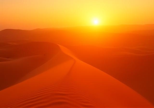 Sun setting over the Sahara dunes with golden ripples